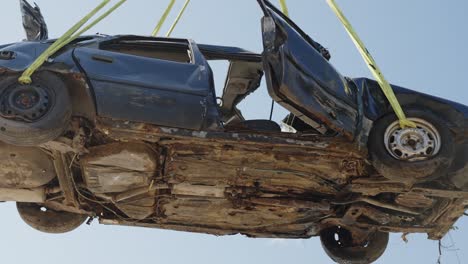 levantando por aire un coche destrozado del depósito de chatarra del vertedero