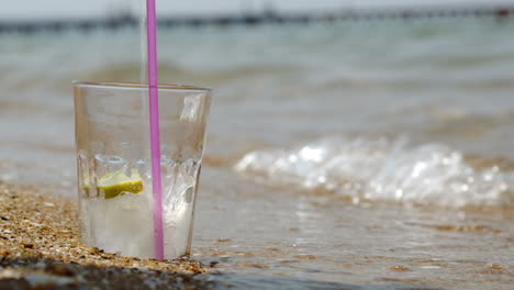 Pouring-fizzy-drink-into-glass-on-the-sand