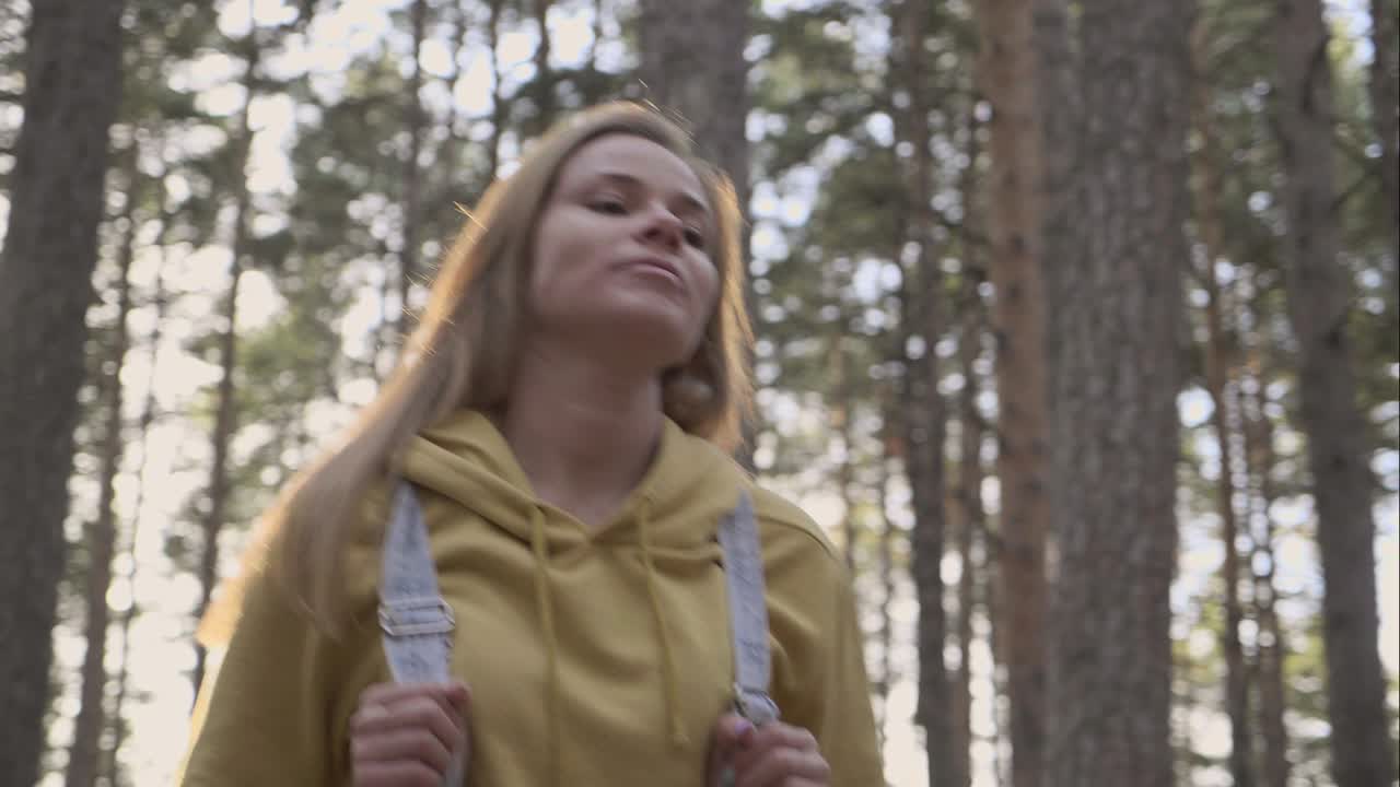 Travel girl walking in autumn forest between trees