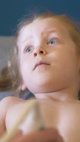 cu: calm little blue eyed girl at abdominal sonogram procedure with professional equipment in light medical office