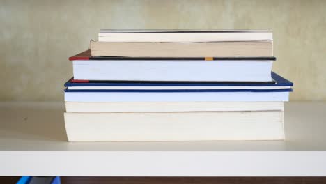 una pila de libros en una estantería blanca