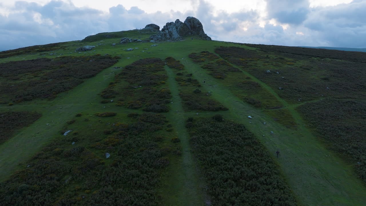 Aerial view of a hilltop with a rock formation and hiking paths