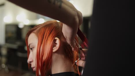 man hairdresser cutting woman's hair in beauty salon. young woman getting her haircut and dressed in hair salon. stylist