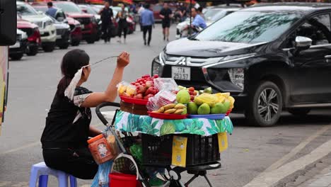 vendor arranges and sells fruit on busy street