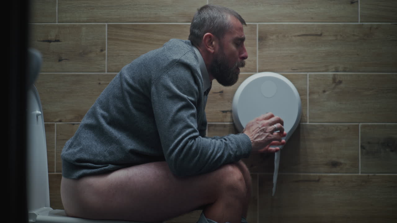 Man Sitting on the Toilet and Suffering From Diarrhea and Stomach Ache in Restroom