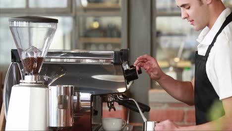 smiling barista steaming milk at the coffee machine