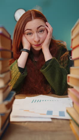 Exhausted-business-woman-looking-at-documents-reports-stacks-of-books-while-working-hard-at-office