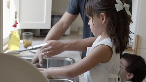 dad helping daughter to wash dish