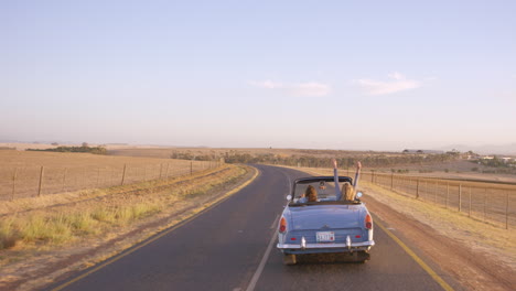 road trip two friends driving  in vintage convertible car on an adventure