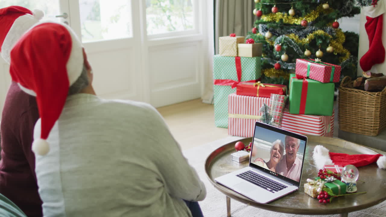 diversas amigas mayores que usan una computadora portátil para una videollamada de navidad con una pareja feliz en la pantalla