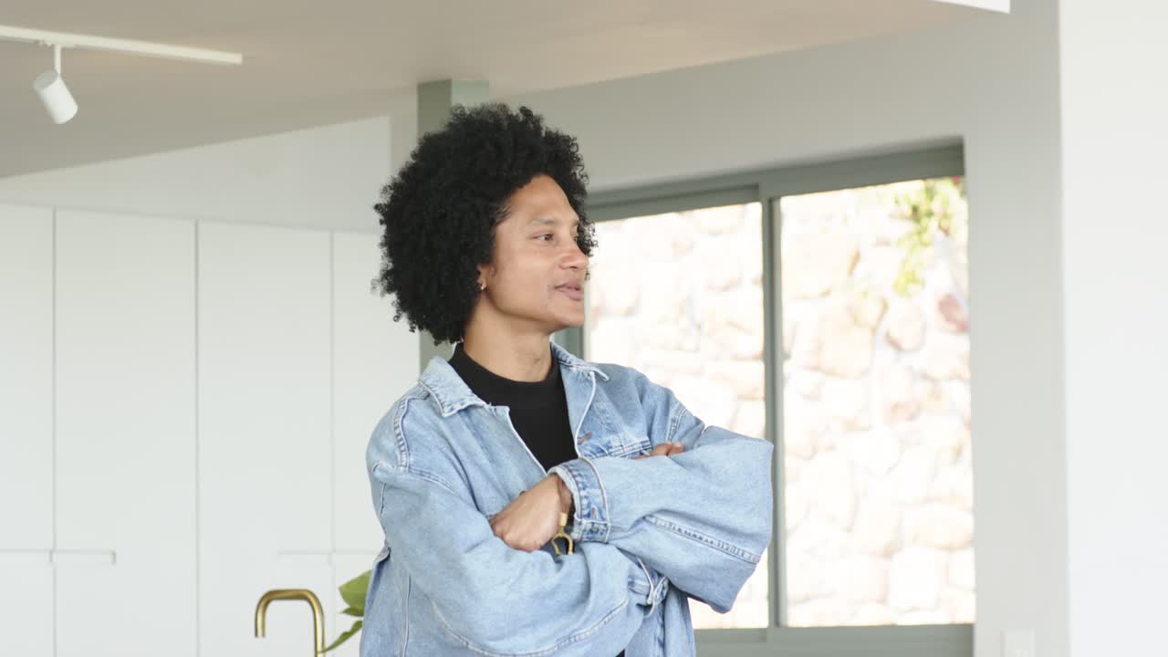 Afro-Amerikaanse man die zich afzet tegen een kookeiland, zich omdraait naar het raam, knikt en het interieur bekijkt