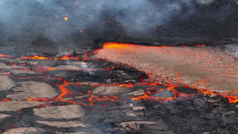 Aerial-close-up-view-of-lava-stream-coming-from-the-volcanic-eruptions-at-Litli-Hrutur,-Iceland,-with-smoke-coming-up