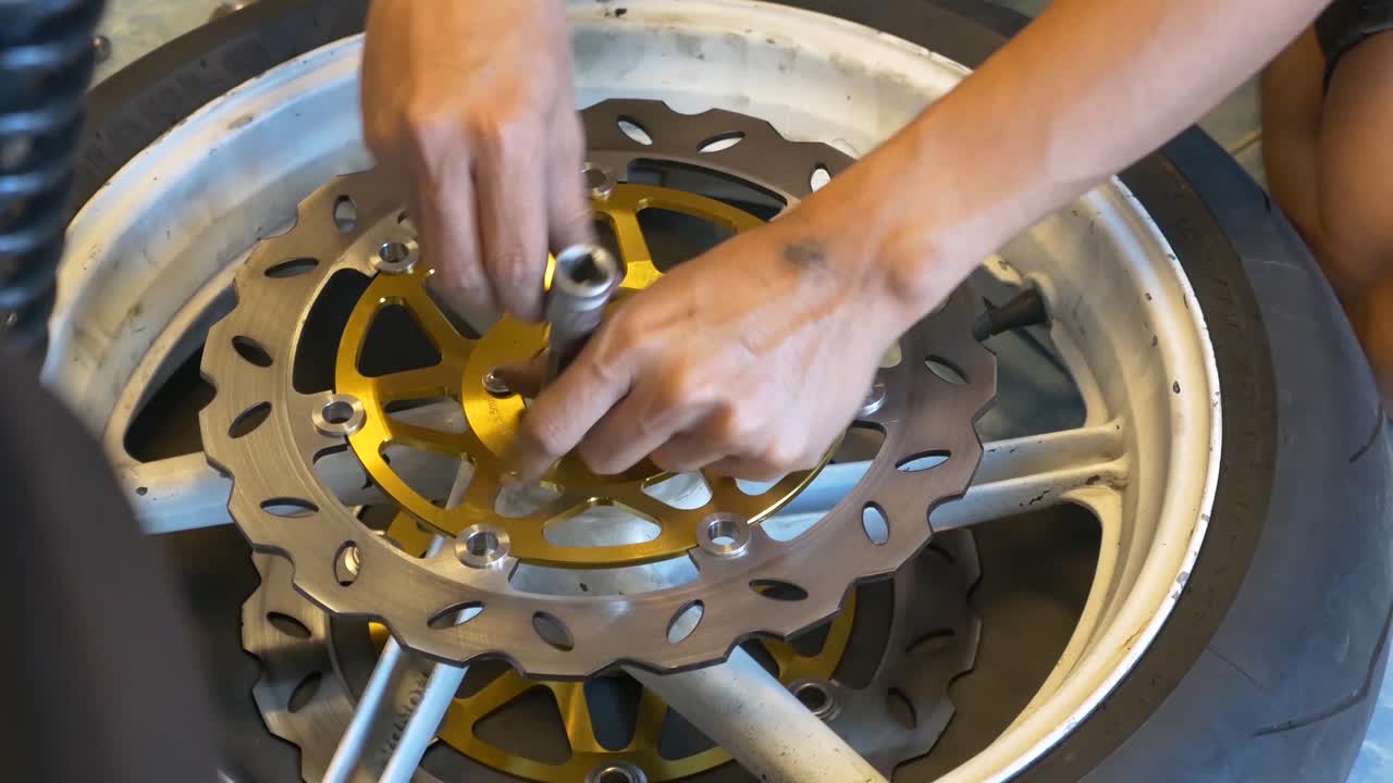 imágenes de primer plano de un mecánico que trabaja en la instalación de frenos de disco para motocicletas