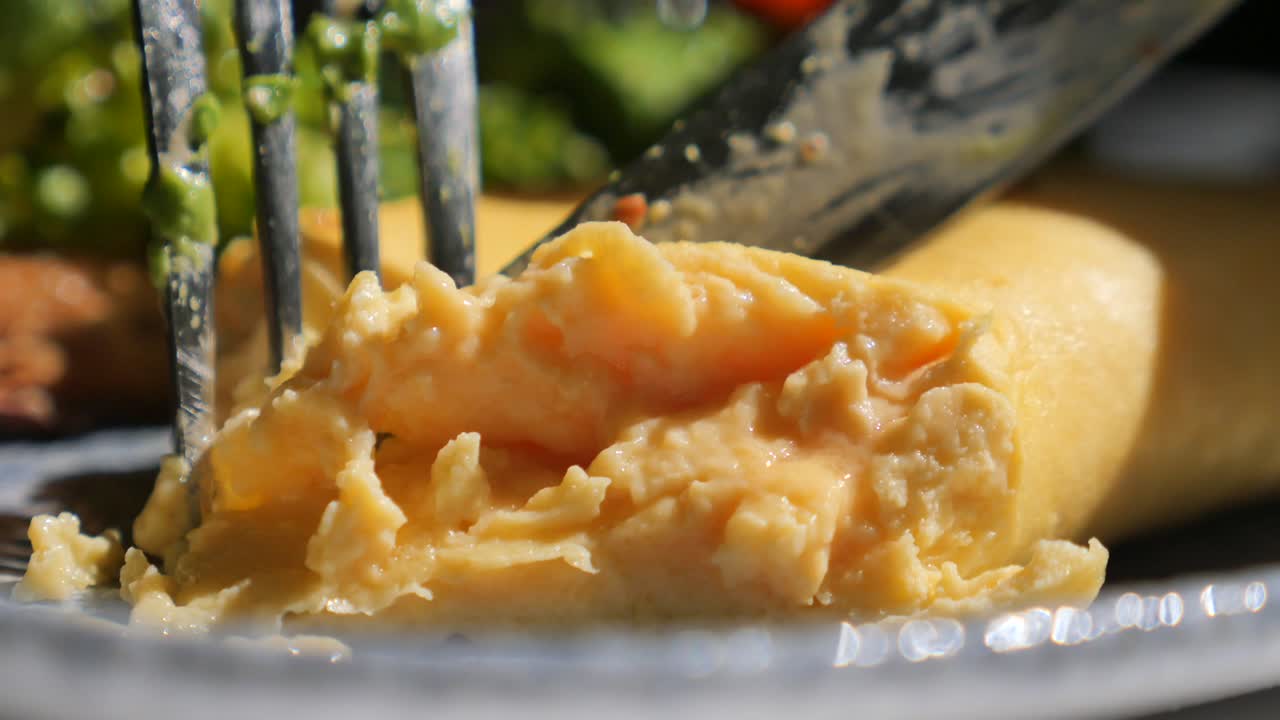 Close-up of an omelette being cut with a knife and fork