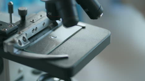 close up of microscope oculars being directed at a sample on a piece of glass. close-up shot of sample slide and microscope with metal lens at laboratory. high quality 4k footage