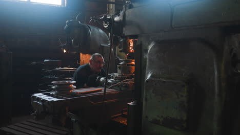 mature worker looks at drilling machine cutting out holes