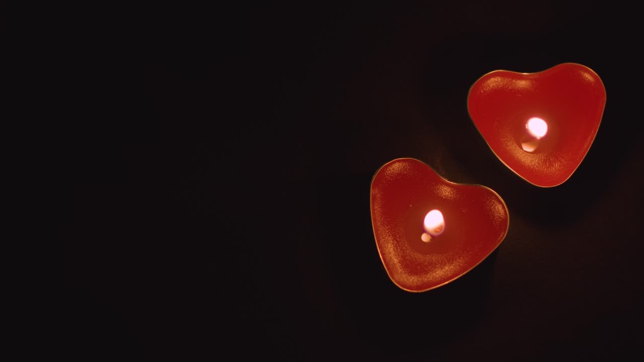 близко к двум романтическим освещенным сердечным красным свечам на черном фоне с копировальным пространством