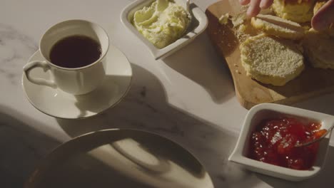 fotografía de estudio de una persona con el tradicional té de la tarde británico con crema de bollos y mermelada 5