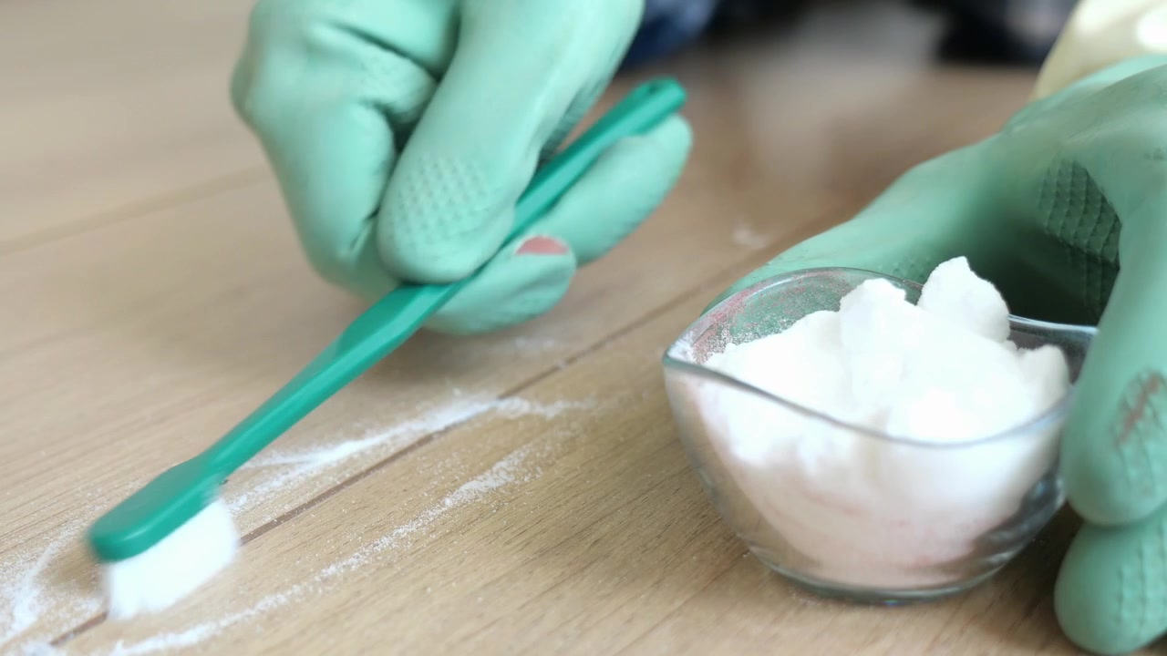 Person Cleaning Grout with Toothbrush and Baking Soda