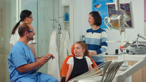 friendly man dentist assistant interrogating kid patient