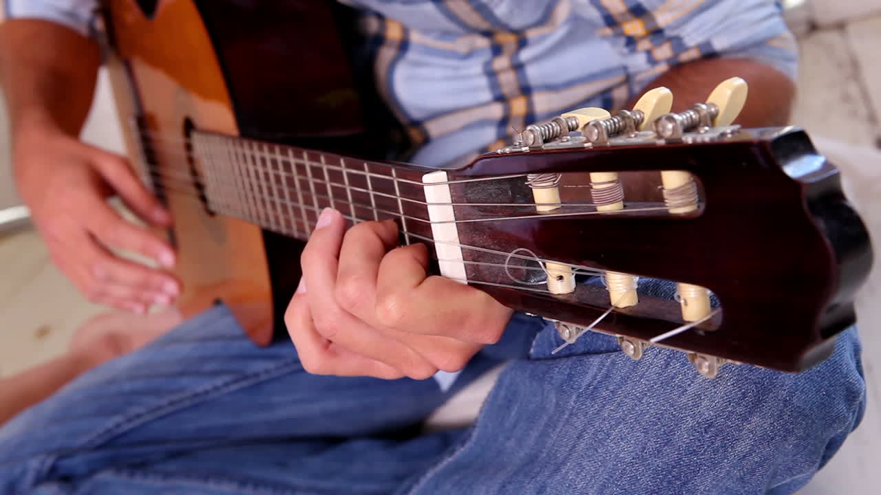 hombre de vaqueros y camisa de cheque tocando la guitarra