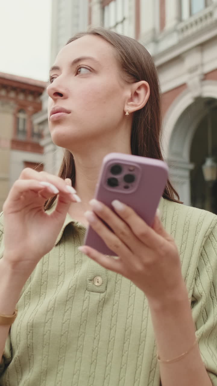 Giovane donna che usa lo smartphone e si guarda intorno in città