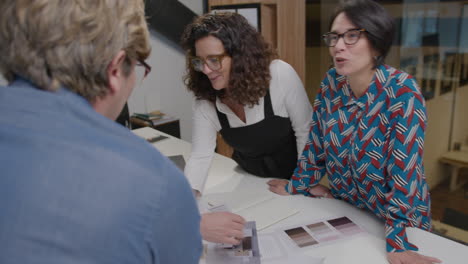 mid-aged female colleagues discussing interior design project with coworkers