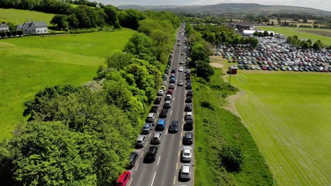 Multi-colored-cars-parked-along-a-lush-green-country-road-during-a-county-fair