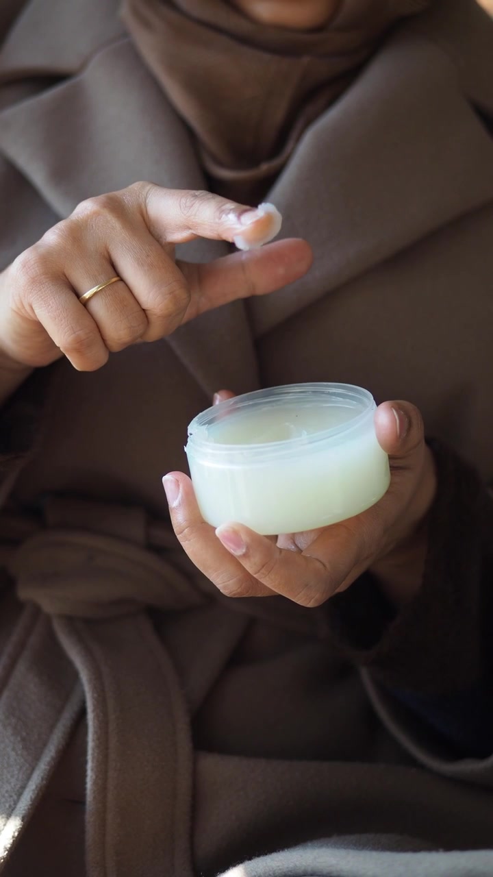Mujer aplicando crema para el cuidado de la piel de un tarro