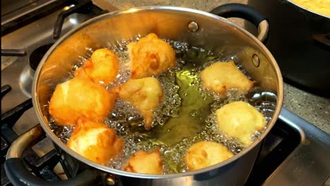 Home-made-Portuguese-donuts-deep-frying-in-a-pan,-4K-60ffs