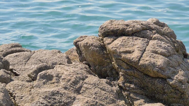 Primo piano dell'acqua dell'oceano dietro una roccia al rallentatore