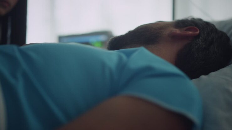 der patient liegt nach der chirurgischen behandlung im bett. besorgter besucher sitzt am mann