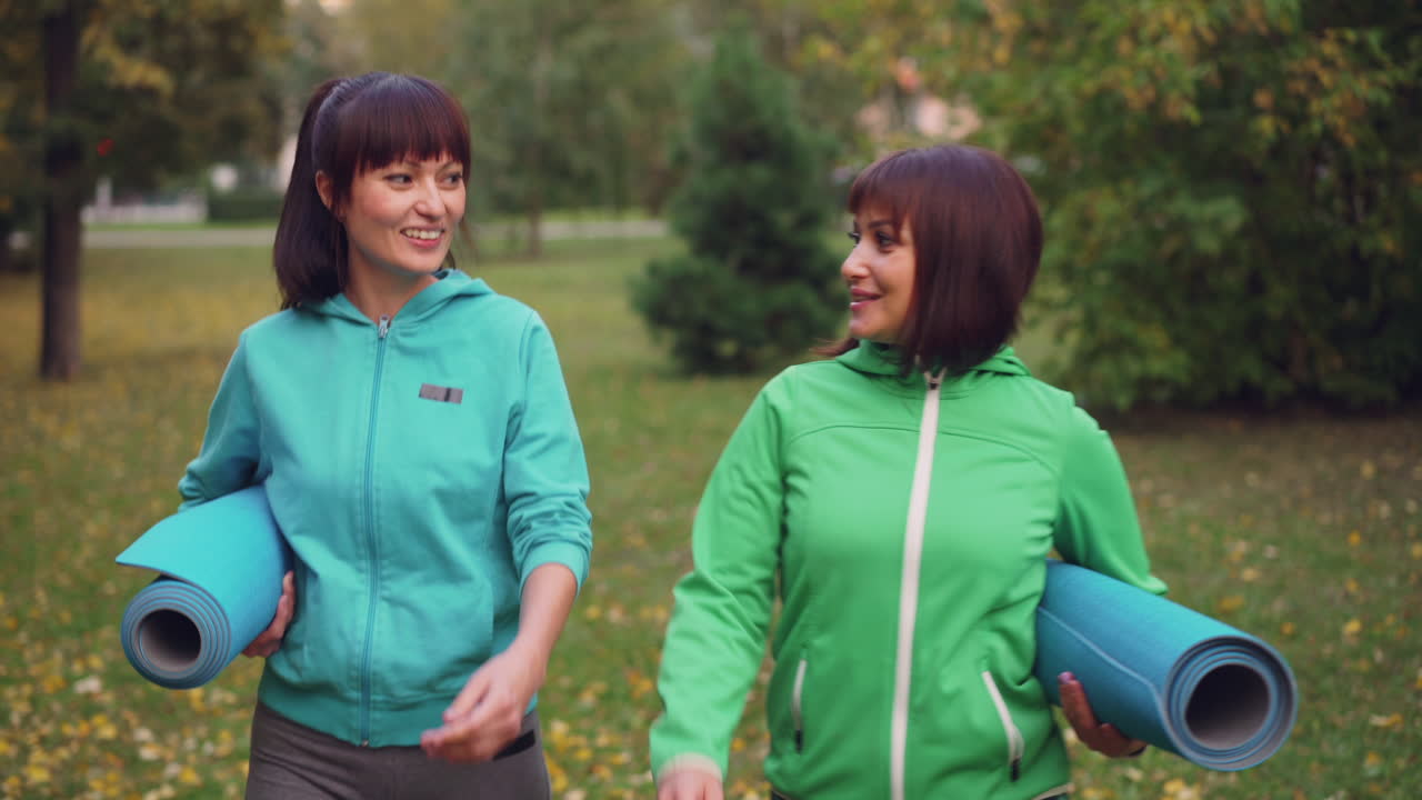 Two Women Walking in Park with Yoga Mats
