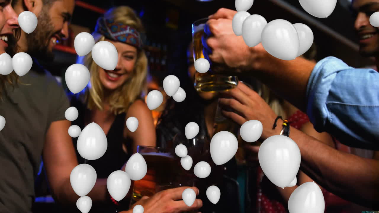 Celebrating with drinks, friends surrounded by white balloons at party gathering