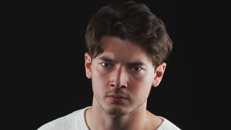 head and shoulders studio shot of unhappy man looking at camera with sad expression in slow motion