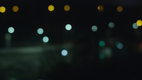 luces de la ciudad nocturna en una ventana abierta, carretera con linternas, fondo borroso
