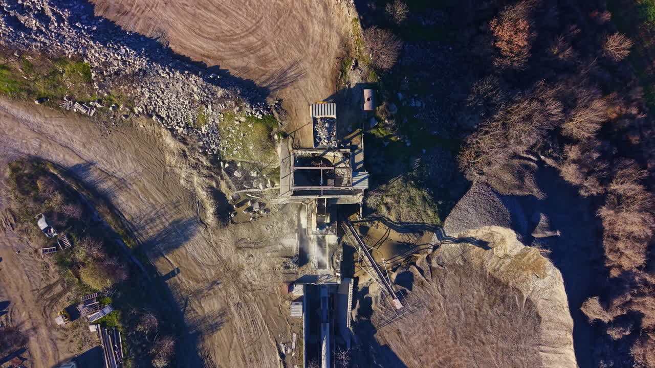 Exploring a gravel quarry landscape under a bright sky, revealing machinery and raw materials in a natural setting