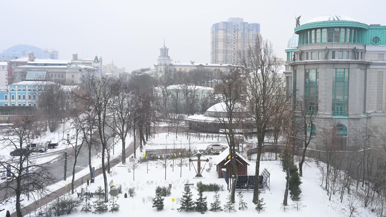 Kyiv, Ukraine: A serene urban landscape blanketed in snow, with bare trees and distant city architecture. This picturesque scene captures the stark beauty of the capital under cold winter skies.