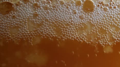 a locked off macro shot of yeast bubbles in active mead fermentation