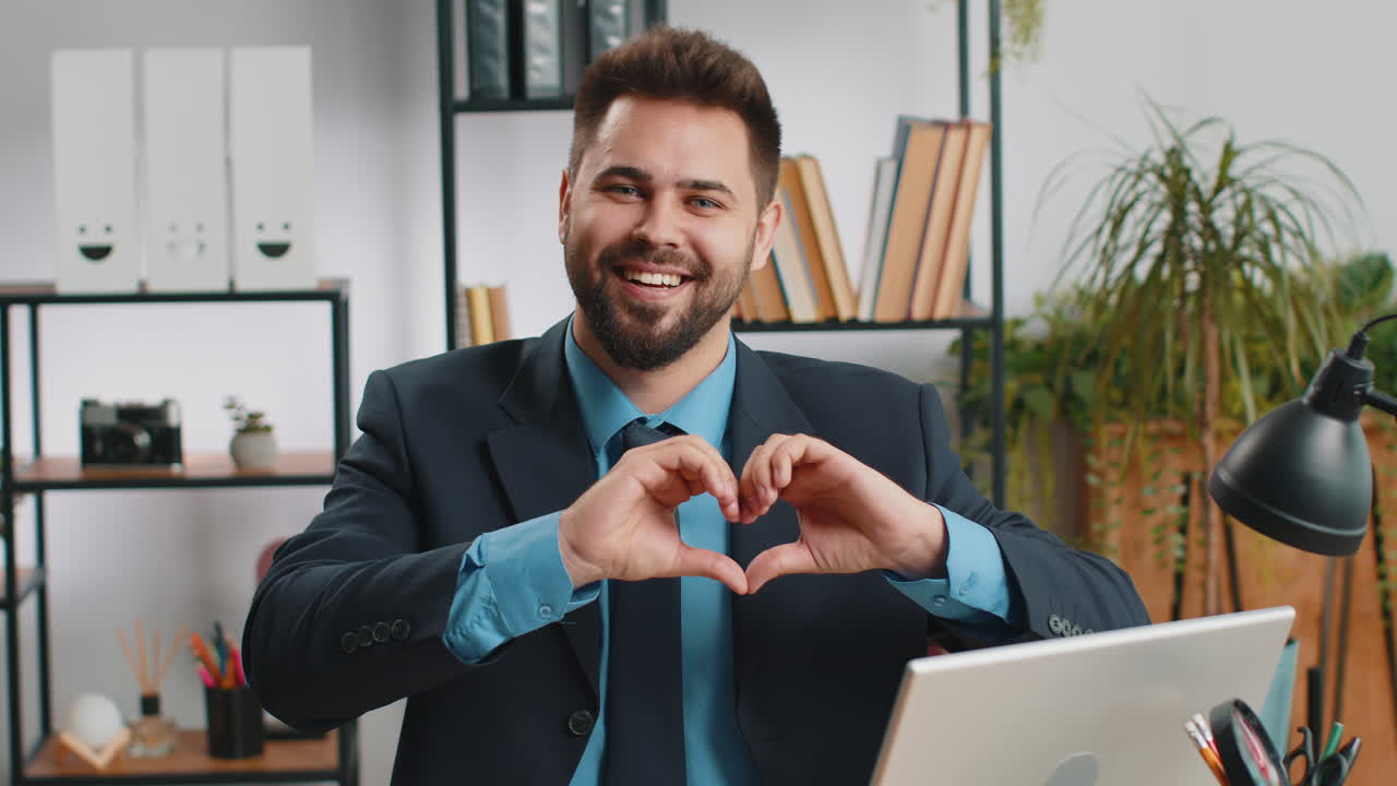 Caucasian business man makes symbol of love showing heart sign to camera express romantic feelings