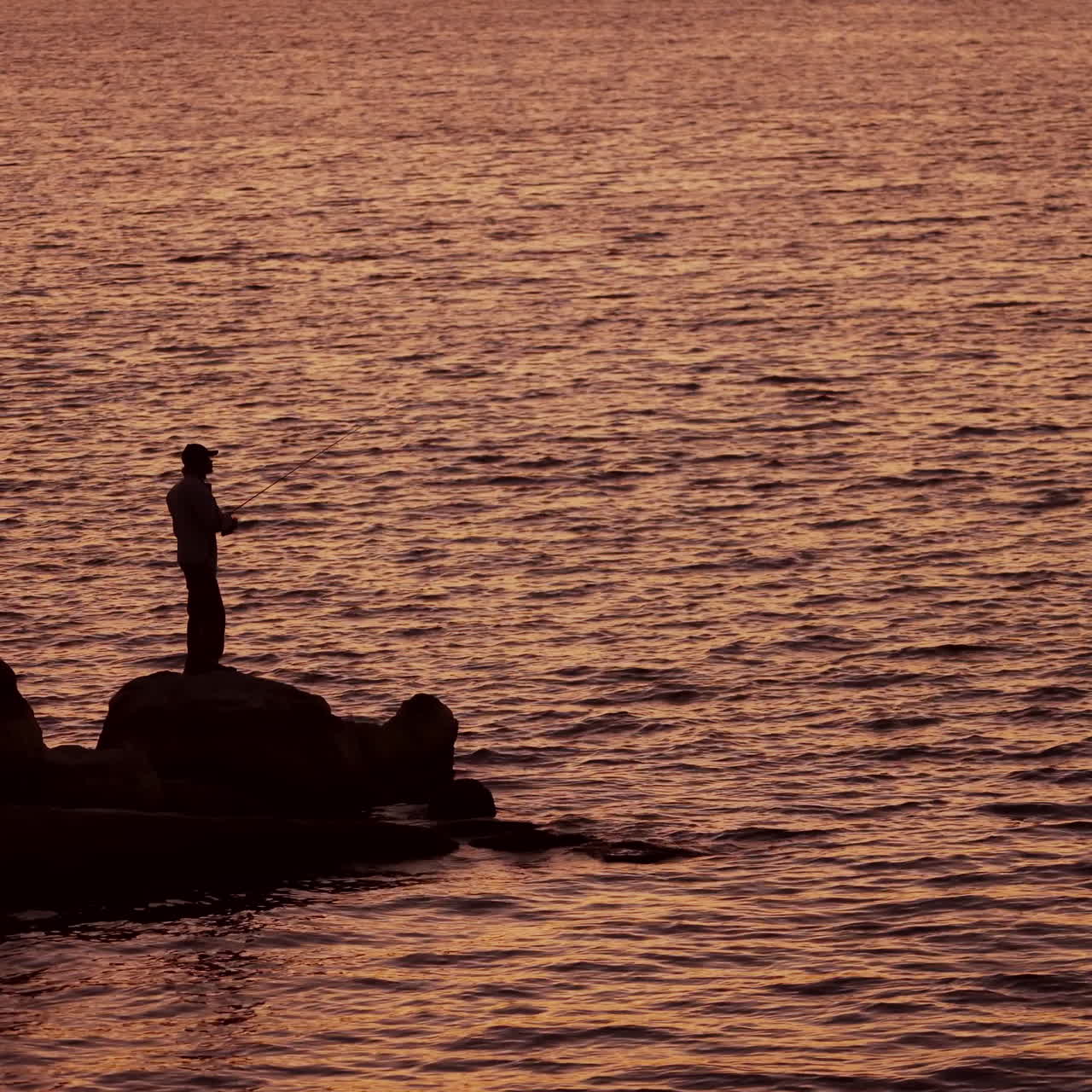 Fishermen on the rocks. Man's silhouette fishing at sunset. Freshwater fishing, catch of fish.