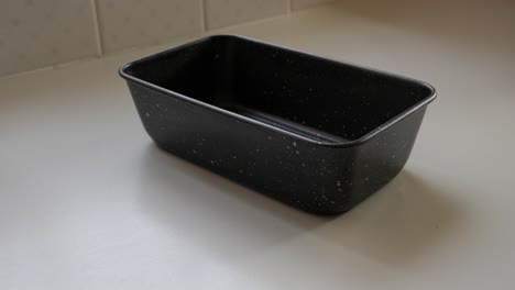 la persona coloca una bandeja de metal en la mesa e intenta alinearla con papel para hornear en el banco de la cocina