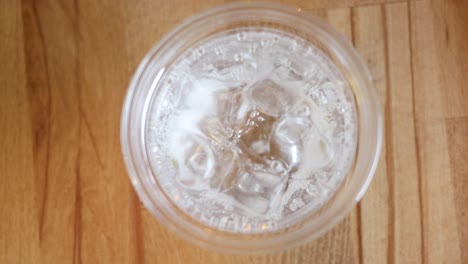 pouring soda water into a cup with ice