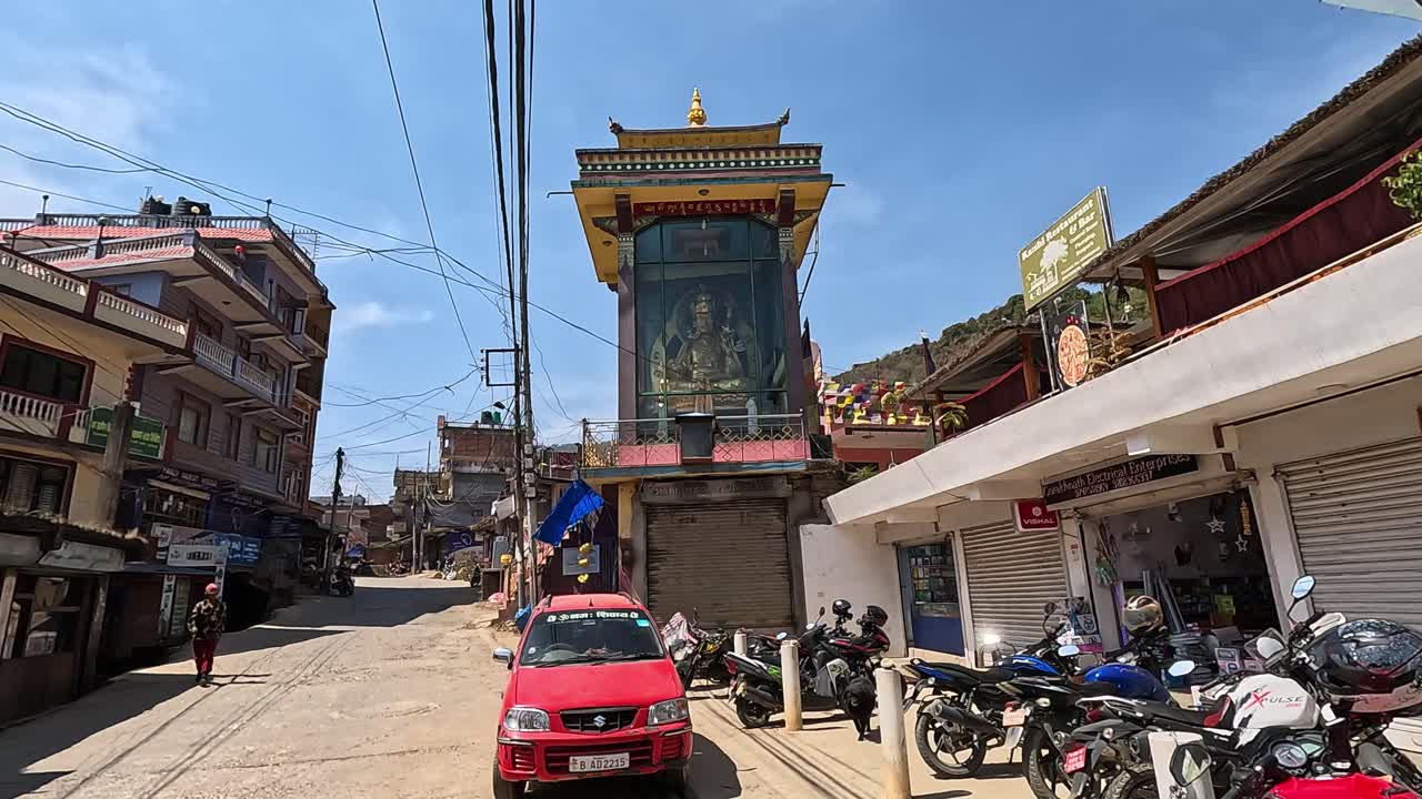 large golden statue of padmasambhava behind an glass temple with traditonal buddhist roof. Streets of Dakshinkali in Nepal