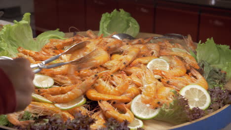 un plato grande lleno de camarones cocidos con hojas de limón y lechuga