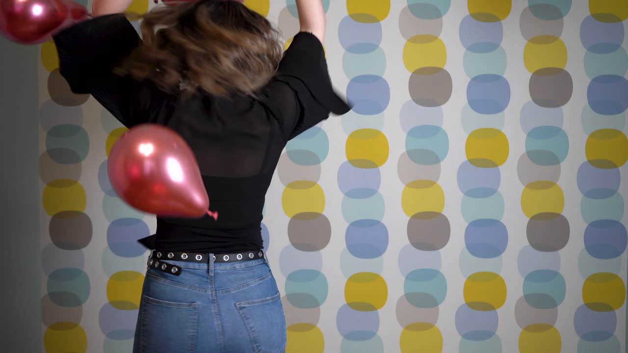 mujer joven bailando frente a globos flotantes en el aire contra un fondo colorido