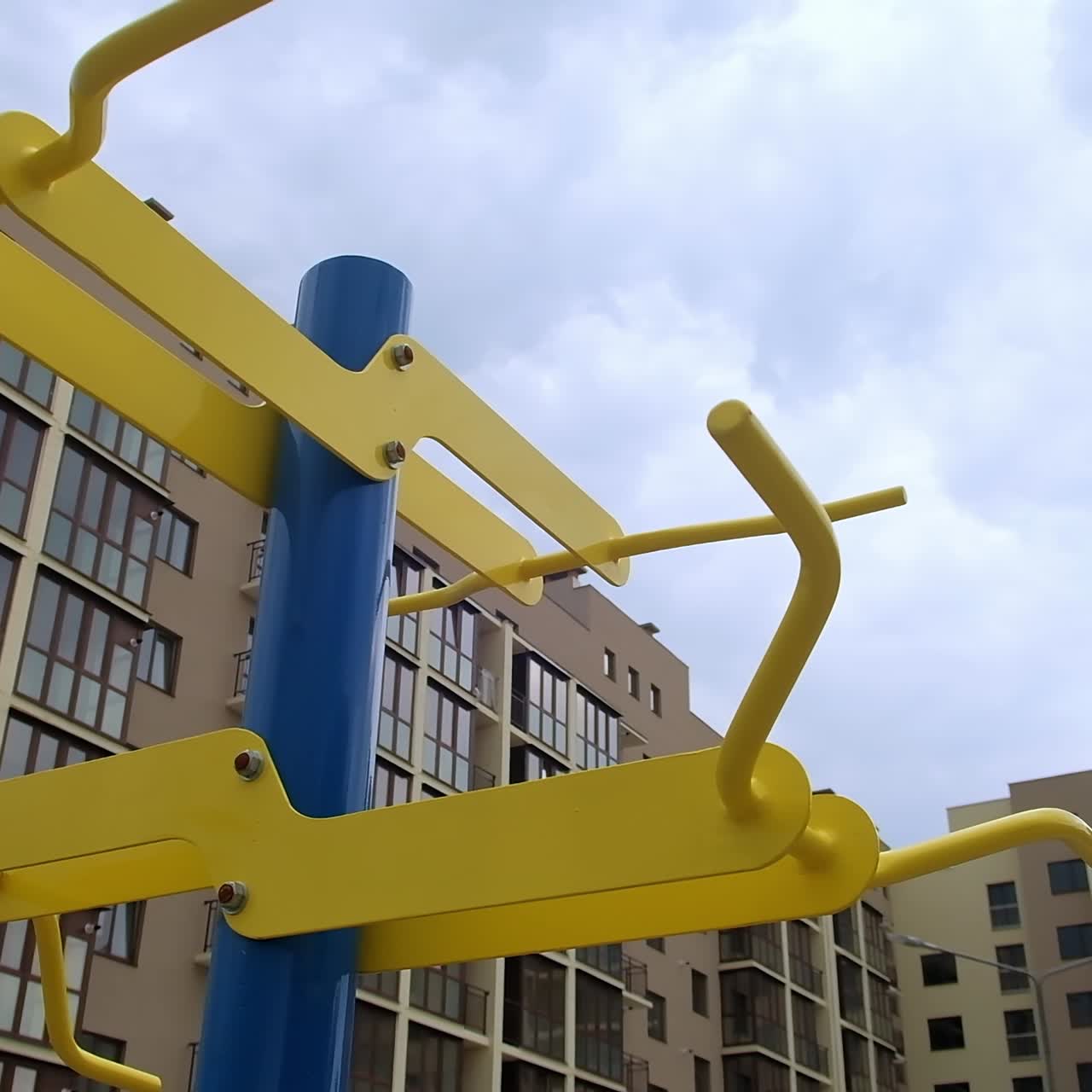 Sbarra orizzontale per allenamento con sullo sfondo un grande edificio residenziale. Attrezzatura sportiva all'aperto vicino al condominio