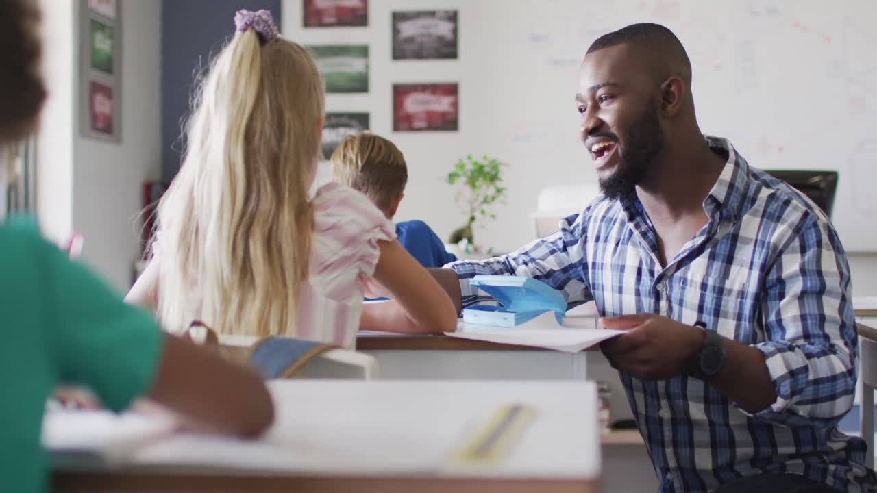 Video di un felice insegnante afroamericano che batte il cinque con una bambina caucasica.