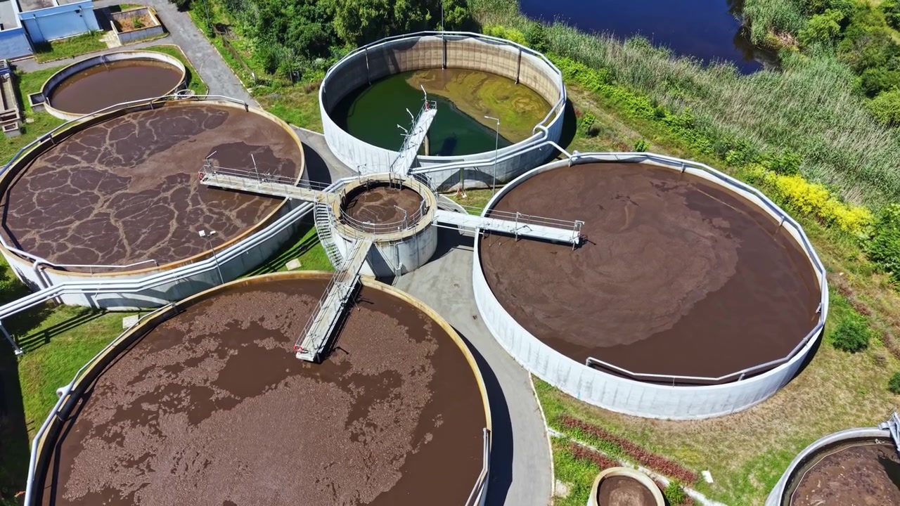 Water treatment facility shows round tanks for processing dirty water in a natural setting during daytime operation