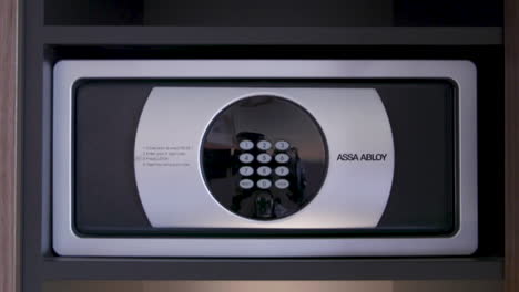 a traveler retrieves a camera from a hotel safe, demonstrating how to access and open the secure storage compartment effectively. this ensures the safety of valuables.